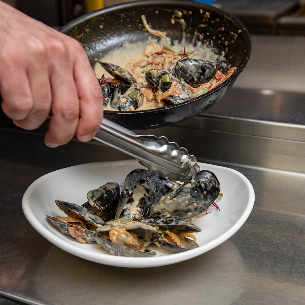 Chef Plating Steamed Mussels at Georges of Galilee